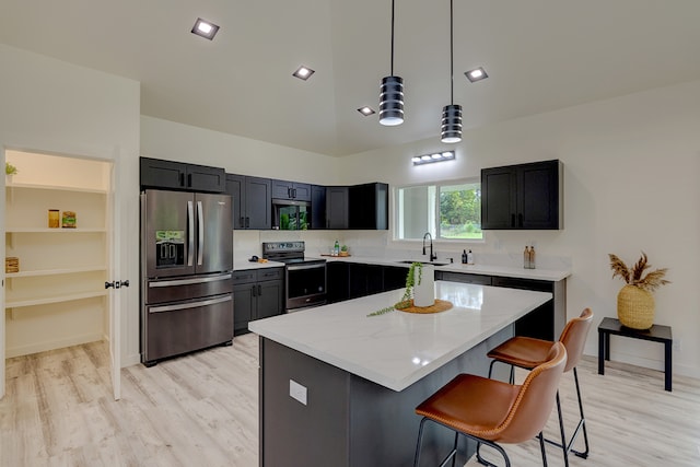 kitchen featuring appliances with stainless steel finishes, light stone counters, pendant lighting, a kitchen island, and a breakfast bar area