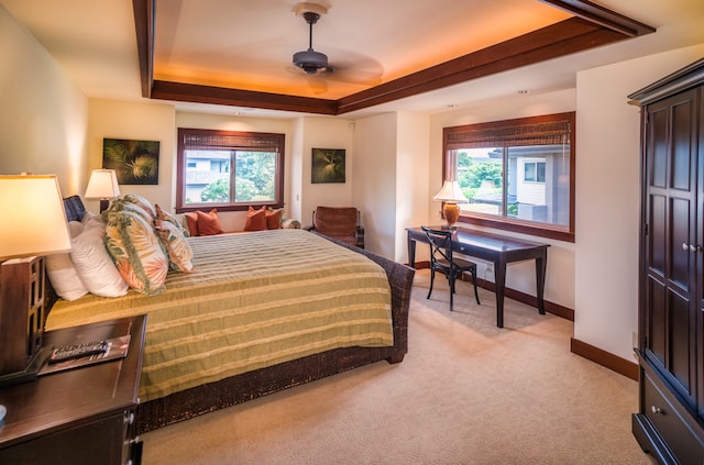 bedroom featuring multiple windows, a tray ceiling, and ceiling fan