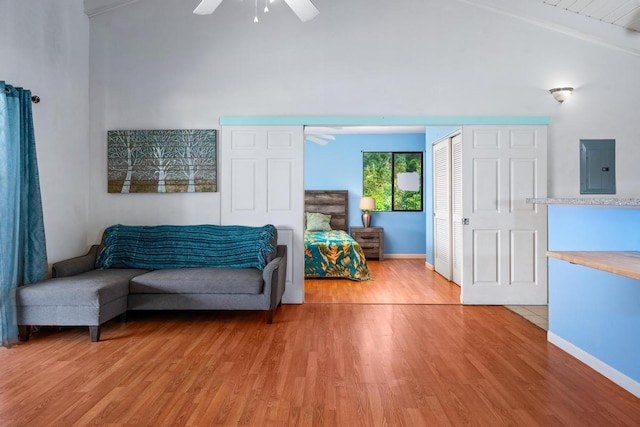 living area with electric panel, ceiling fan, lofted ceiling with beams, and hardwood / wood-style flooring