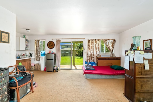 bedroom with stainless steel refrigerator, light carpet, and access to outside