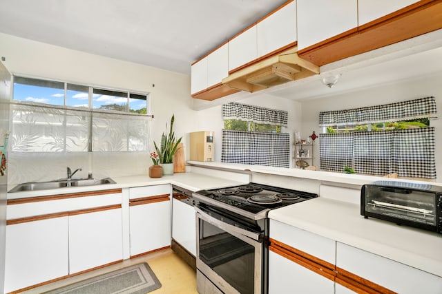 kitchen featuring white cabinets, sink, plenty of natural light, and electric stove