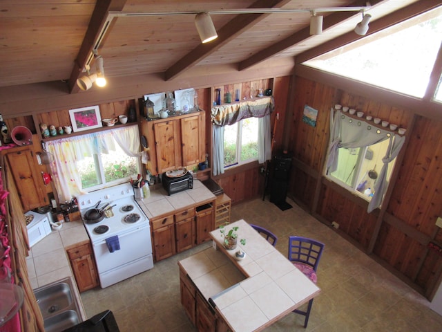 kitchen with tile countertops, plenty of natural light, and wood walls