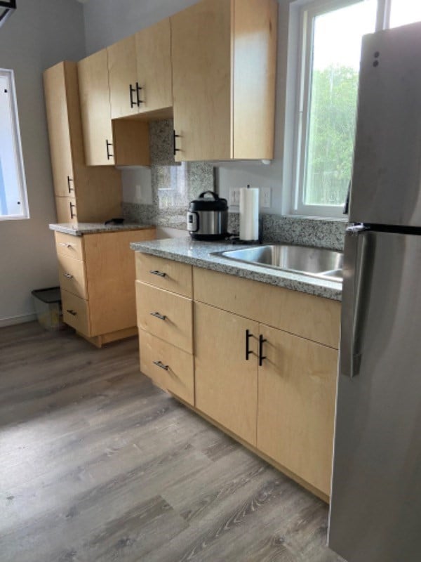 kitchen featuring light brown cabinetry, stainless steel fridge, and light hardwood / wood-style floors