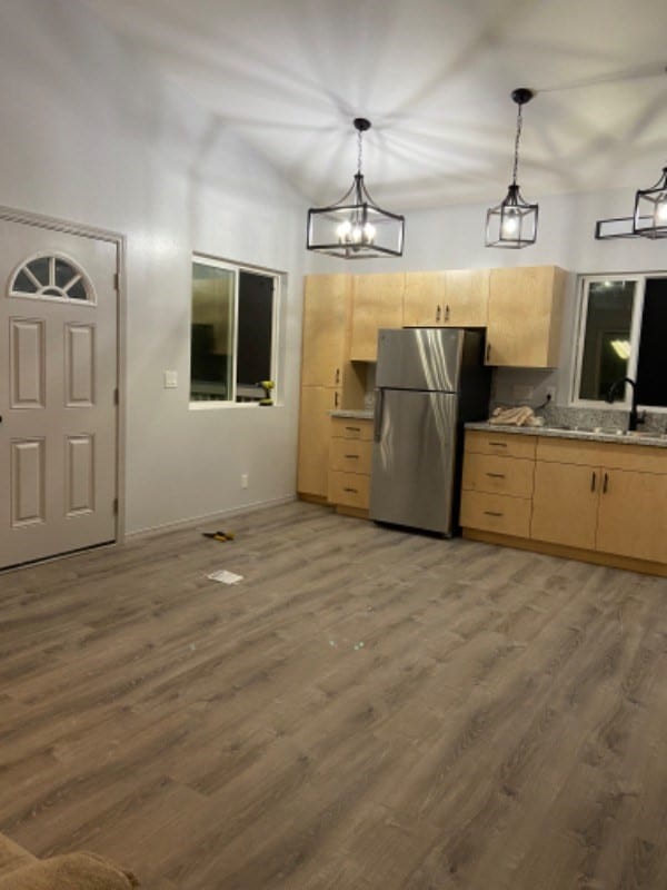 kitchen with light brown cabinets, hanging light fixtures, and stainless steel refrigerator