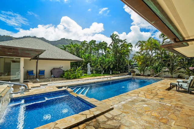 view of pool with a patio, a mountain view, and an in ground hot tub