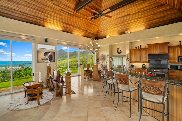 kitchen featuring stainless steel appliances, wood ceiling, a towering ceiling, decorative light fixtures, and a wall mounted air conditioner