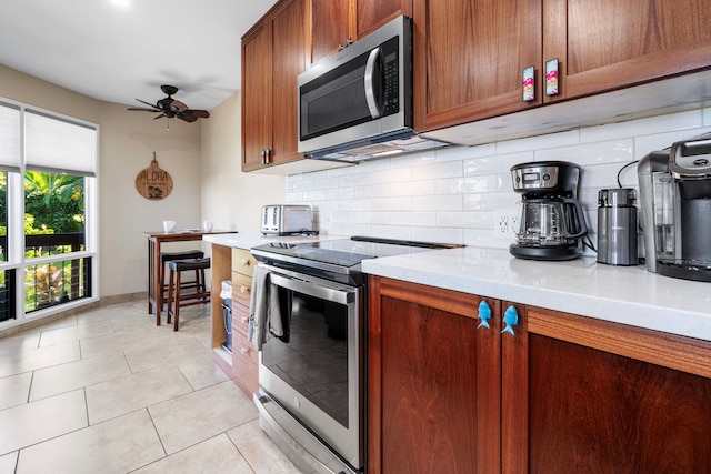 kitchen featuring stainless steel appliances, light tile patterned flooring, ceiling fan, and backsplash