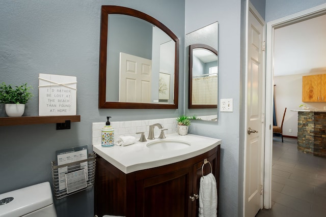 bathroom with vanity, toilet, and decorative backsplash