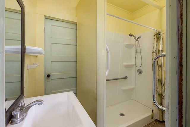 full bath with a shower stall, ornamental molding, and a sink