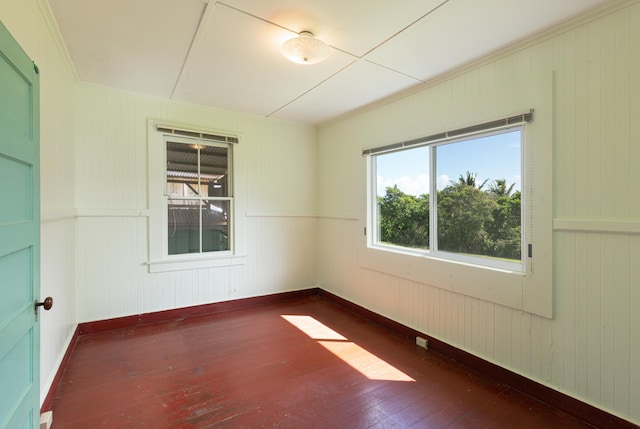 spare room featuring crown molding, baseboards, and wood-type flooring