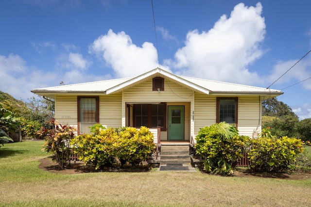 bungalow-style home featuring a front lawn and metal roof