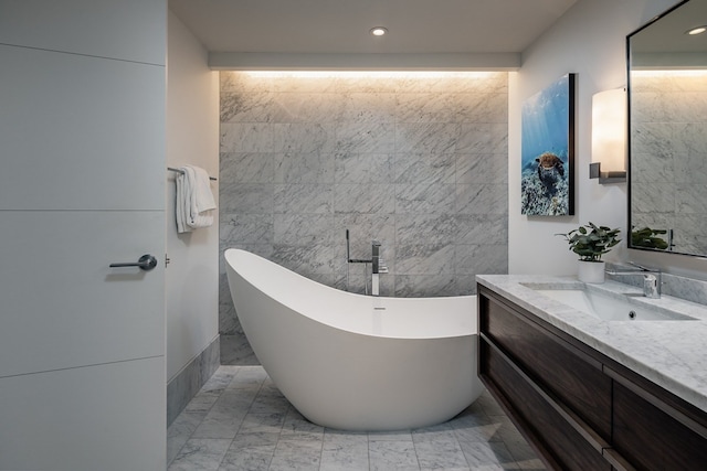 bathroom with tile walls, vanity, and a tub