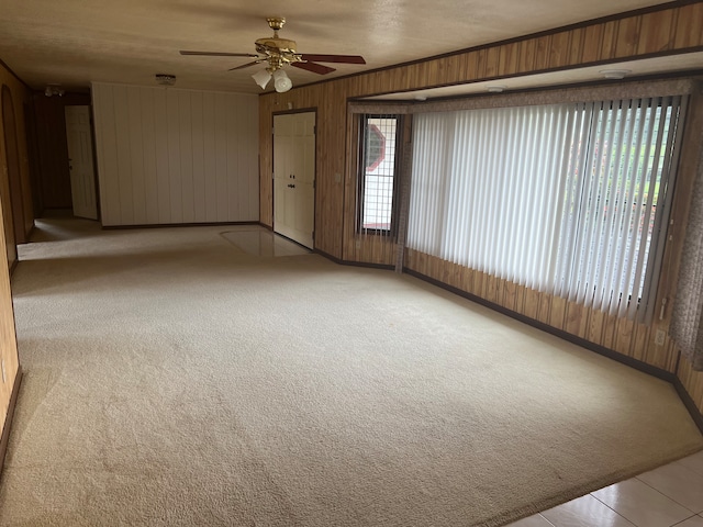 carpeted spare room with wooden walls and ceiling fan