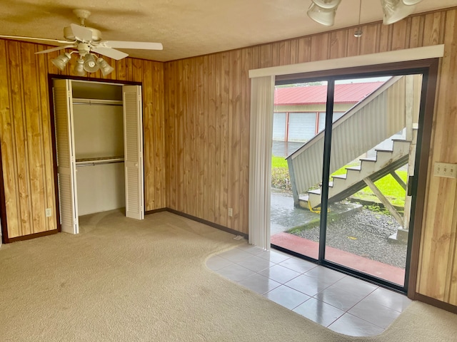 entryway featuring wood walls, light tile patterned floors, and ceiling fan