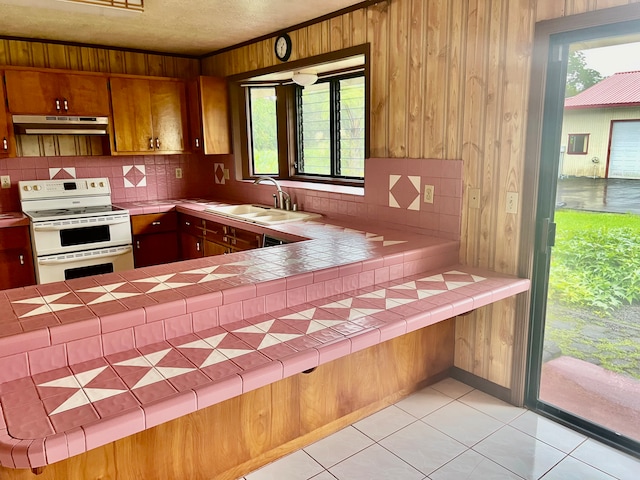 kitchen with tile countertops, electric stove, and wooden walls