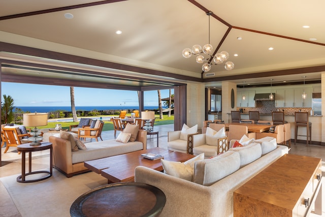 living room featuring a water view, a healthy amount of sunlight, lofted ceiling, and a chandelier