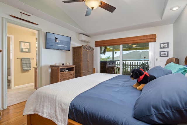 bedroom with access to exterior, ceiling fan, a wall mounted AC, ensuite bathroom, and hardwood / wood-style floors