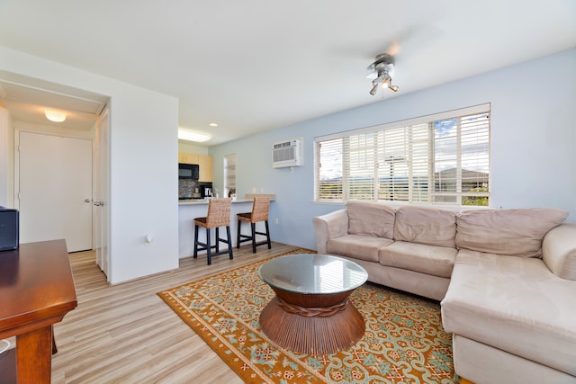 living room with an AC wall unit and light wood-type flooring