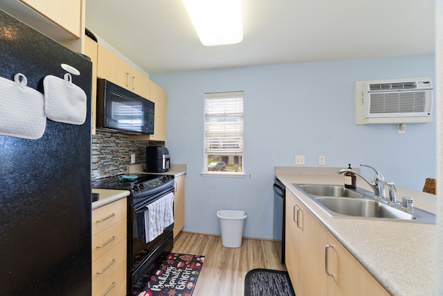 kitchen featuring black appliances, sink, an AC wall unit, light wood-type flooring, and light brown cabinetry