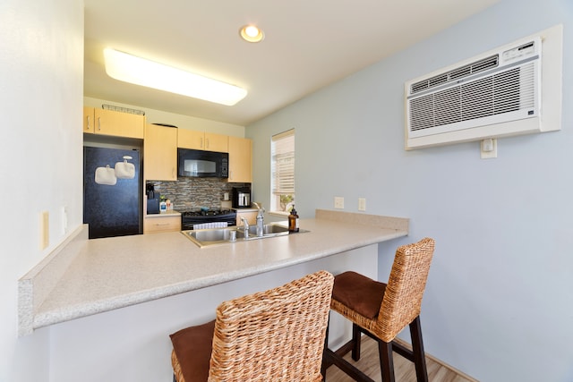 kitchen featuring light hardwood / wood-style floors, black appliances, a kitchen breakfast bar, backsplash, and an AC wall unit