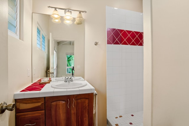 bathroom featuring a wealth of natural light, vanity, and tiled shower