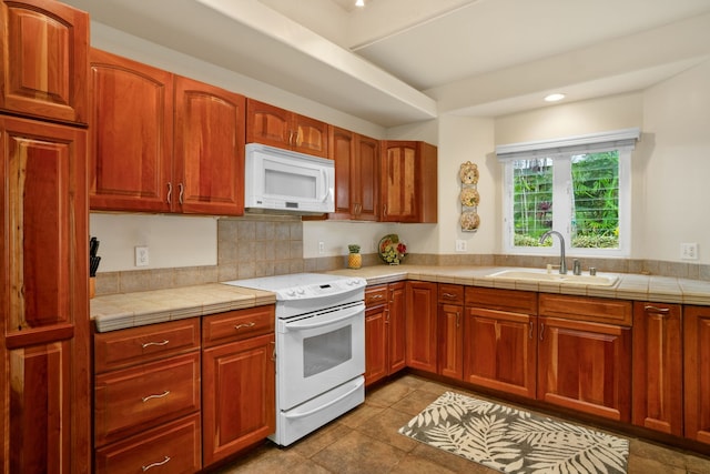 kitchen featuring white appliances, sink, tile counters, and light tile patterned floors