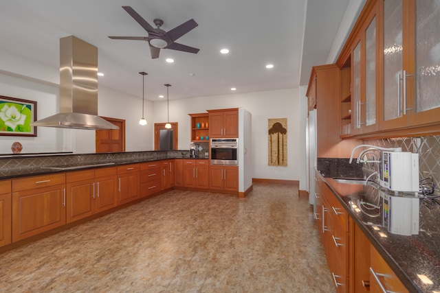 kitchen featuring pendant lighting, stainless steel oven, sink, tasteful backsplash, and island range hood
