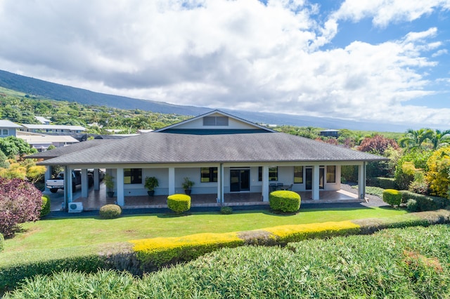 back of house featuring a lawn, a mountain view, and a patio