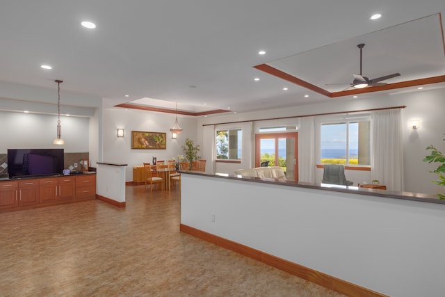 kitchen featuring a tray ceiling, ceiling fan, and pendant lighting