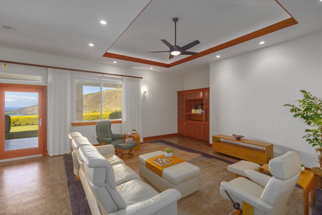 living room featuring ceiling fan and a tray ceiling