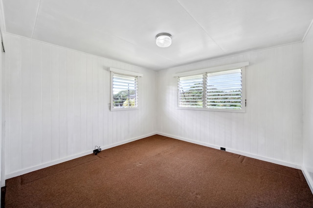 carpeted spare room with wooden walls