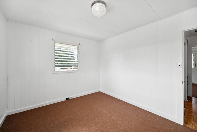 spare room featuring wood walls and carpet