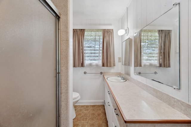 bathroom featuring vanity, a shower with door, toilet, and a wealth of natural light