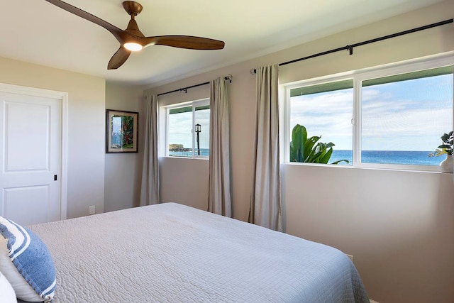 bedroom featuring ceiling fan, a water view, and a view of the beach