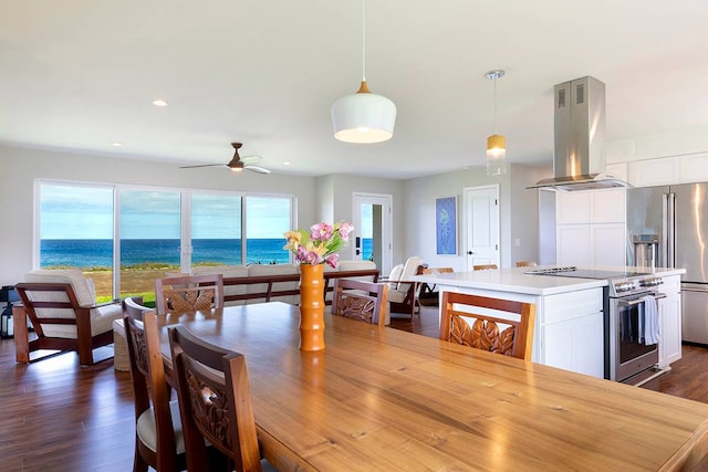 dining area with ceiling fan, a water view, and dark hardwood / wood-style floors