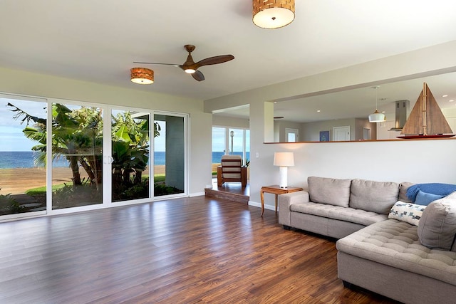 living room with a wealth of natural light, a water view, and dark wood-type flooring