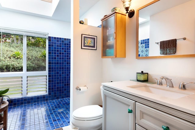 bathroom with vanity, a shower, tile patterned floors, a skylight, and toilet