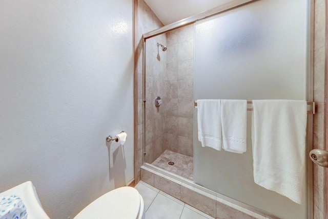 bathroom featuring tile patterned flooring, toilet, and an enclosed shower