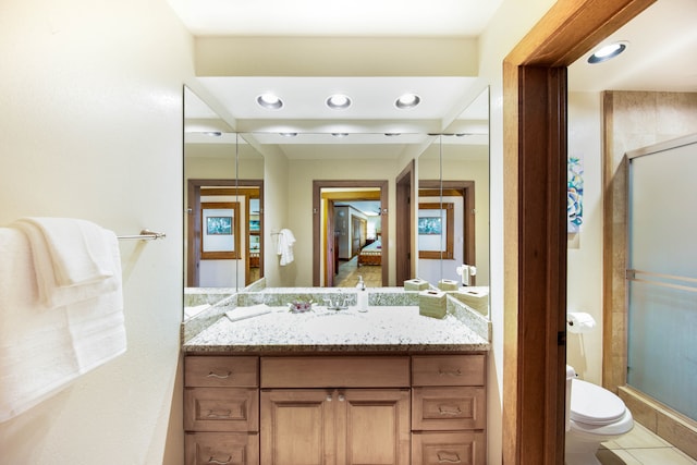 bathroom with tile patterned floors, vanity, toilet, and a shower with door