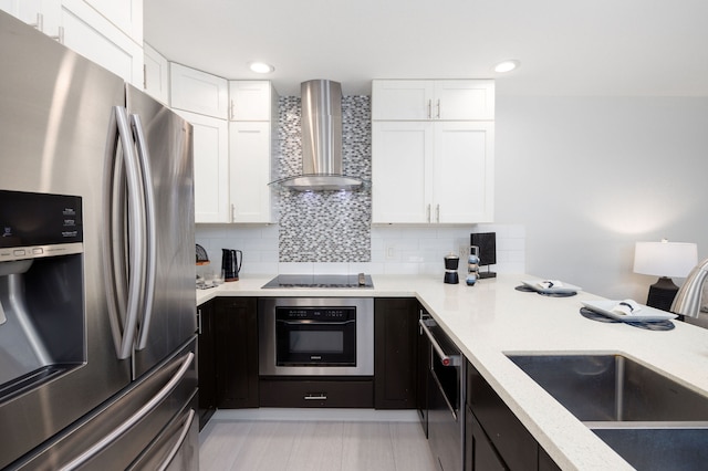 kitchen with stainless steel appliances, white cabinetry, sink, wall chimney exhaust hood, and decorative backsplash