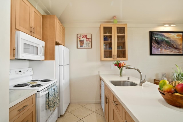 kitchen with light tile patterned flooring, light brown cabinets, white appliances, and sink