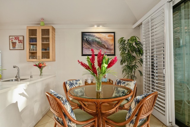 dining space featuring light tile patterned flooring, lofted ceiling, and sink