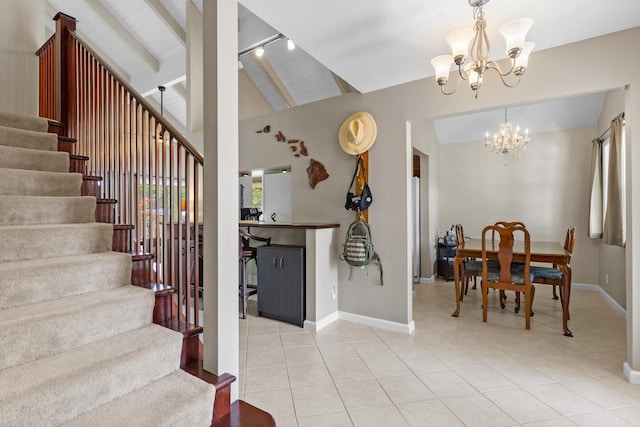 tiled foyer entrance featuring track lighting, vaulted ceiling, and an inviting chandelier