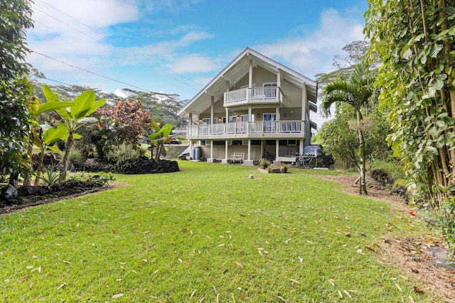 back of property with a lawn and a balcony