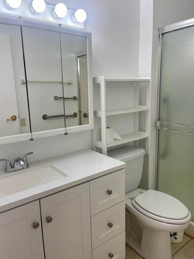 bathroom with tile patterned flooring, vanity, toilet, and a shower with door