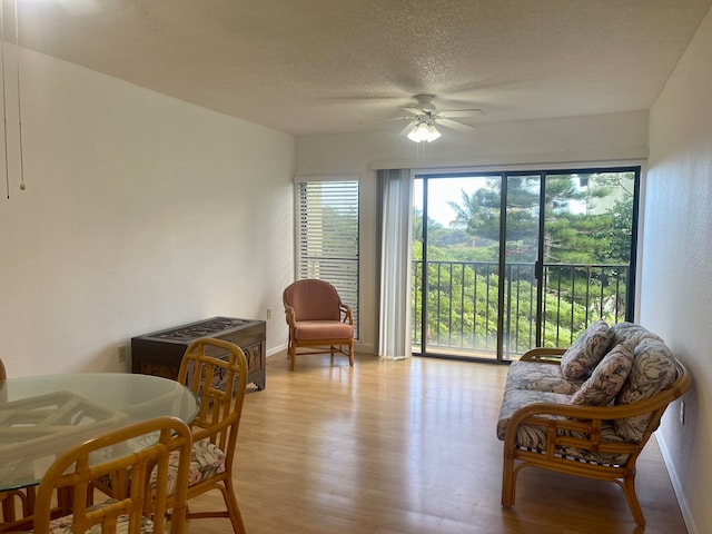 living area featuring ceiling fan, a textured ceiling, and light hardwood / wood-style floors