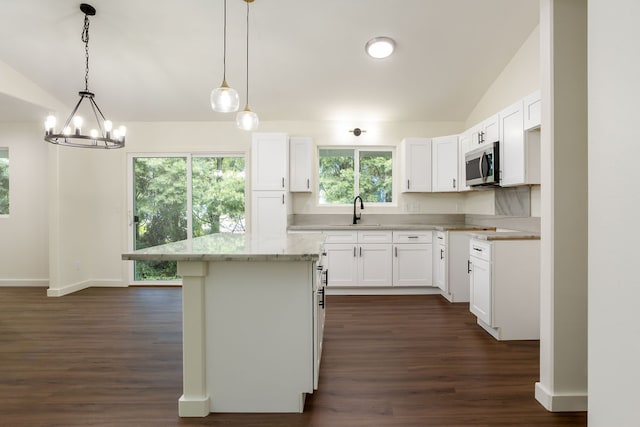 kitchen with white cabinetry, pendant lighting, a kitchen island, and vaulted ceiling