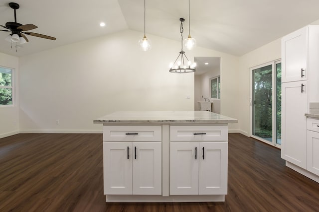 kitchen featuring lofted ceiling, pendant lighting, light stone counters, dark hardwood / wood-style floors, and white cabinetry