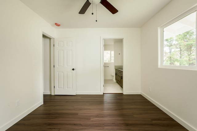 unfurnished bedroom with ensuite bathroom, dark hardwood / wood-style flooring, and ceiling fan