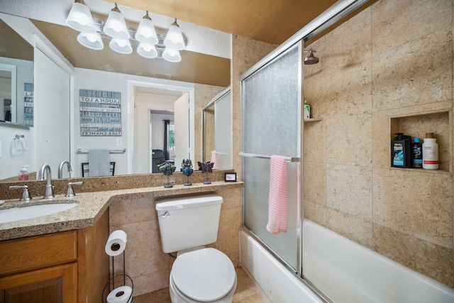 full bathroom with tile patterned flooring, enclosed tub / shower combo, toilet, vanity, and tile walls